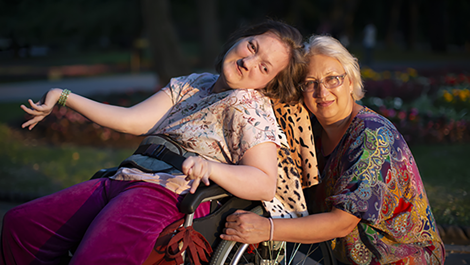 En rullstolsbunden flicka i sällskap med en kvinna